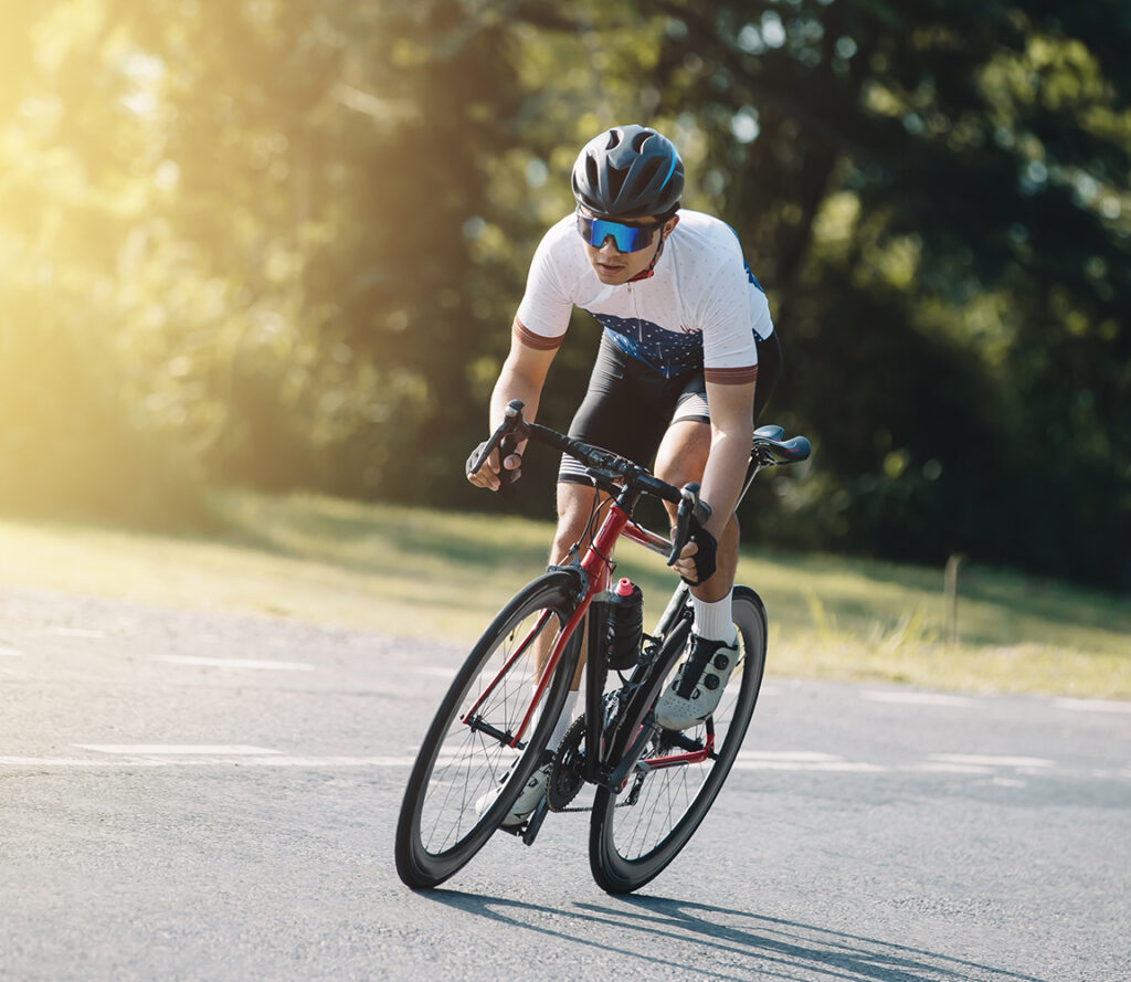Cyclist pedaling on a racing bike outdoors in sun set .The image
